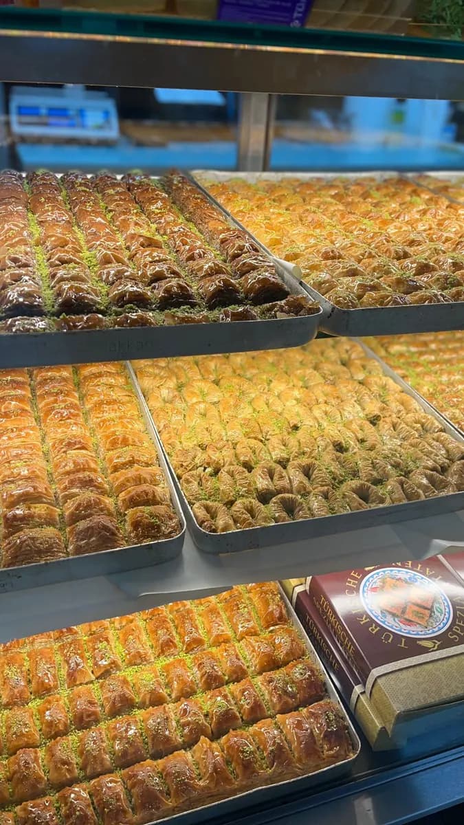 Baklava-Vitrine mit mehreren Sorten auf großen Blechen.
