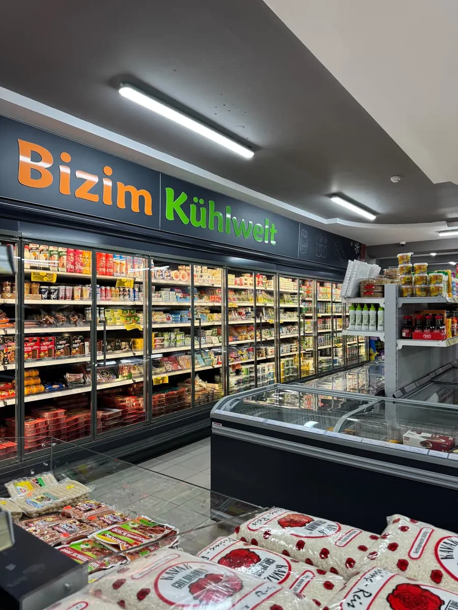 Bizim Kühlwelt mit Joghurt, Ayran und Käse hinter Glastüren, davor die Kühltruhe.
