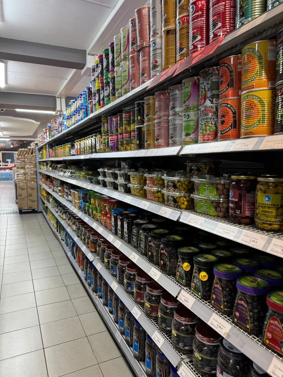 Langer Gang mit Konserven, Ölen und eingelegtem Gemüse in dichten Reihen.